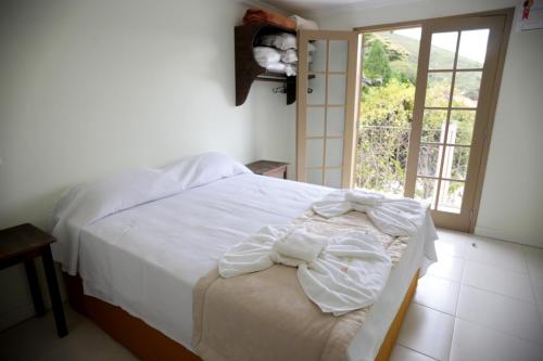 a white bed in a room with a window at Flats Martinez in Conservatória