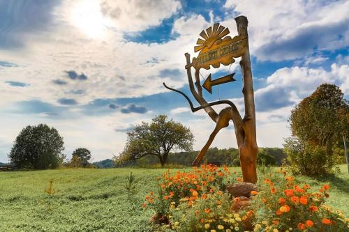 a wooden sign in a field with flowers at Saullēkti ozolos pie Ežezera in Ezernieki