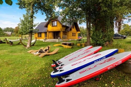 a group of surfboards sitting on the grass in front of a house at Saullēkti ozolos pie Ežezera in Ezernieki
