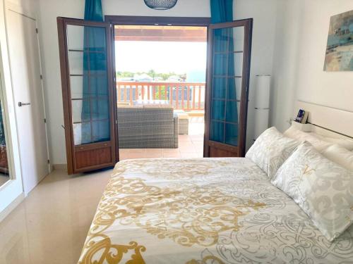 1 dormitorio con 1 cama y puerta a un balcón en Luxury 4-Bedroom Villa With Heated Pool + Sea View, en Playa Blanca