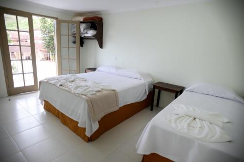 um quarto com 2 camas e lençóis brancos em Residencial Mb em Conservatória