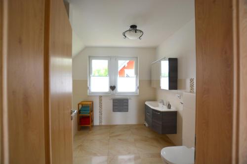 uma casa de banho com um lavatório, um WC e uma janela. em Urlaub am Plätlinsee Haus Rike em Wustrow