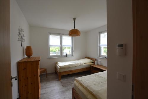 a bedroom with a bed and a desk and two windows at Urlaub am Plätlinsee Haus Rike in Wustrow