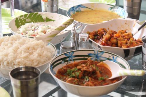 a table topped with bowls of food and rice at The Inchara Hill View HomeStay in Chikmagalūr