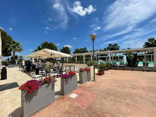 a patio with tables and chairs and an umbrella at Masseria Grottella in Avetrana