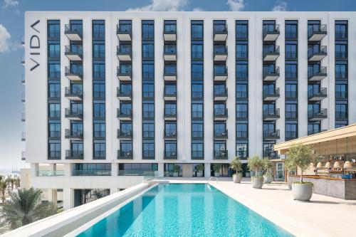 uma imagem de um hotel com uma piscina em frente a um edifício em Vida Beach Resort Marassi Al Bahrain em Manama