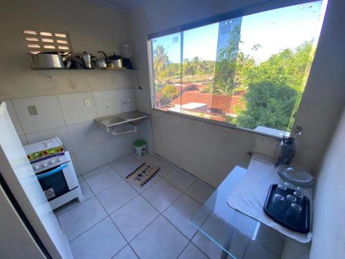 eine Küche mit einem großen Fenster und einem weißen Fliesenboden in der Unterkunft Sibauma Aparts in Pipa