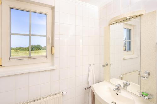 a white bathroom with a sink and a mirror at Ferienapartment-ruegen in Neddesitz