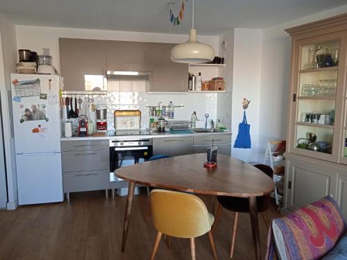 une cuisine avec une table en bois et un réfrigérateur dans l'établissement Appartement Cosy Terrasse vue Quai Canal + parking, à Sète