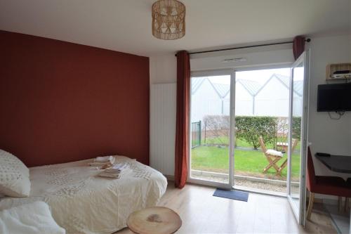 a bedroom with a bed and a sliding glass door at Jardin - à 50m de la plage - Wifi - Parking in Courseulles-sur-Mer