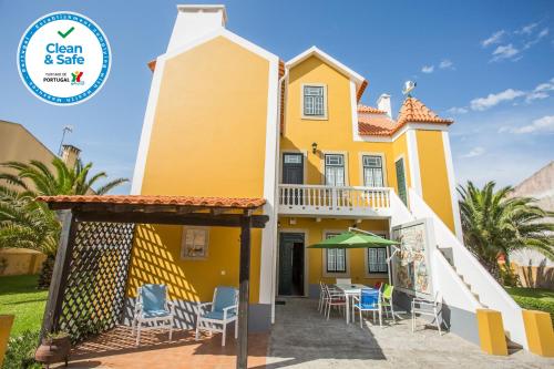 a yellow house with chairs and tables in front of it at Torreira . Yellow Beach Pavilion in Torreira