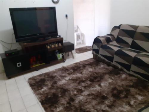 Una sala de estar con un sofá y un televisor de pantalla plana. en Santo Ivo, en Aparecida