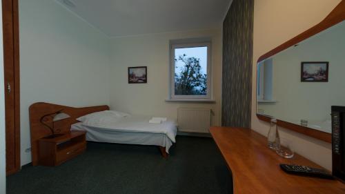 a bedroom with a bed and a desk and a television at Pieprz & Wanilia Noclegi in Murowana Goślina