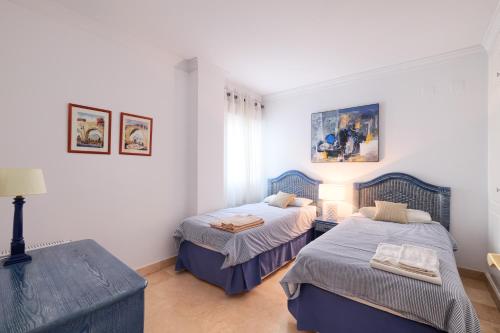 een slaapkamer met 2 bedden en een tafel met een lamp bij Beach Side 2 Bedroom apartment in La Gavia San Pedro in Marbella