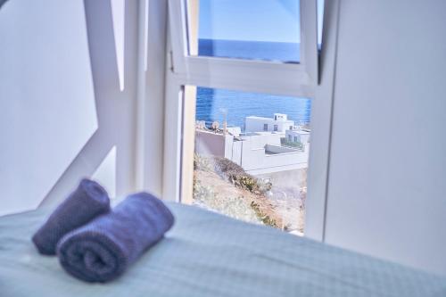 Una cama con dos toallas moradas sentadas junto a una ventana. en 2BDR Comfy Apartment with Ocean View, en Porís de Abona