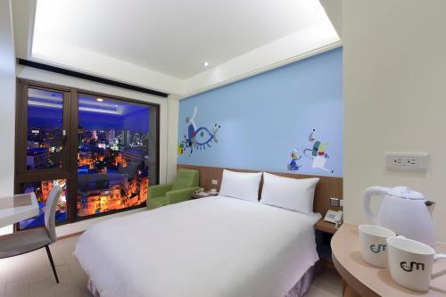 a bedroom with a large white bed and a window at Hotel MU in Zhongli