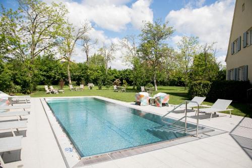 a swimming pool with white chairs next to a building at Residenz Velich in Apetlon