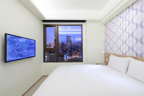 a white bedroom with a large bed and a window at Hotel MU in Zhongli