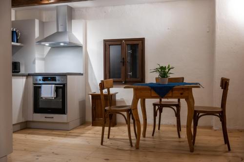 a kitchen with a wooden table with chairs and a stove at Tschardakenhof Appartements in Lutzmannsburg