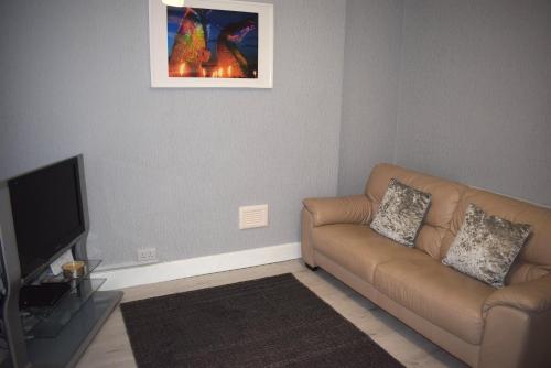 a living room with a couch and a flat screen tv at Kelpies Serviced Apartments- Robertson in Falkirk