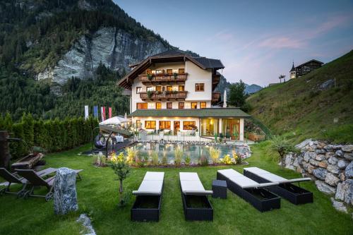 una casa su una collina con panchine nell'erba di Naturhotel Hüttenwirt im Grossarltal a Hüttschlag