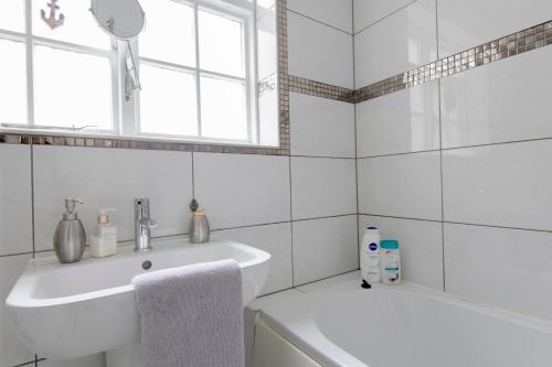a white bathroom with a sink and a tub at Fantastic 3 Bed Brighton House- Sleeps 6- SUPERFAST WiFi and Garage in Brighton & Hove