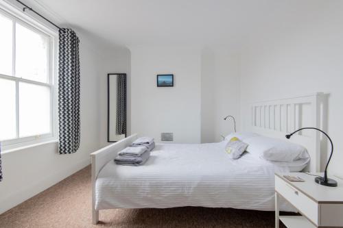 a white bedroom with a white bed and a desk at Fantastic 3 Bed Brighton House- Sleeps 6- SUPERFAST WiFi and Garage in Brighton & Hove