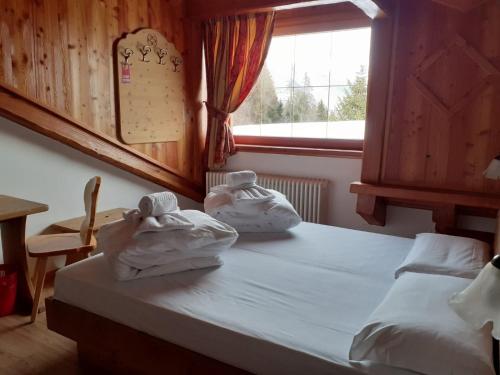a bedroom with two towels on a bed with a window at Hotel Dal Bracconiere in Folgarida