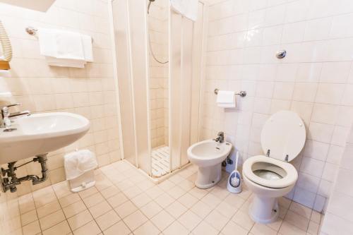 a white bathroom with a toilet and a sink at Il Castagno in Orciano di Pesaro