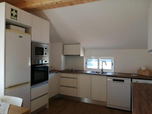 eine Küche mit weißen Schränken und einem weißen Kühlschrank in der Unterkunft Lar Dos Guerreiros in Vila Nova de Milfontes