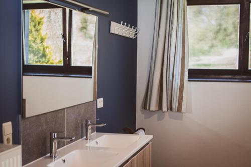 La salle de bains est pourvue de 2 lavabos et de 2 fenêtres. dans l'établissement La petite maison du moulin de Scoville., à Hamois