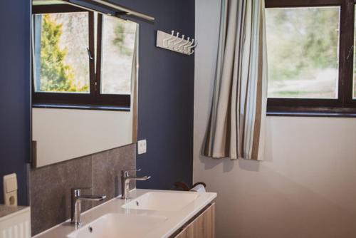 a bathroom with two sinks and two windows at La petite maison du moulin de Scoville. in Hamois