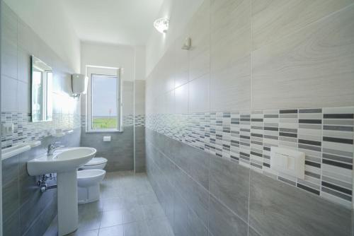 a white bathroom with a sink and a toilet at Residence Emmesse in Zambrone