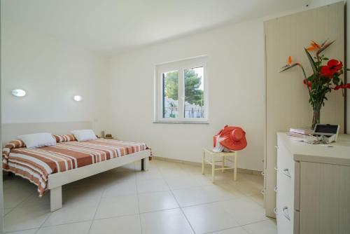 a white bedroom with a bed and a window at Residence Emmesse in Zambrone