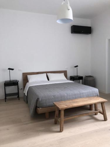 een slaapkamer met een bed en een houten bank bij whiterooms in Cesena