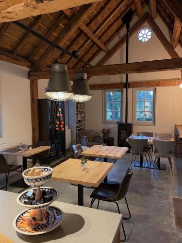 a dining room with tables and chairs and windows at Hof van Eersel in Eersel