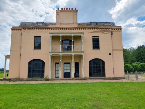 an old house with a grass field in front of it at Moggerhanger Park, Moggerhanger in Sandy