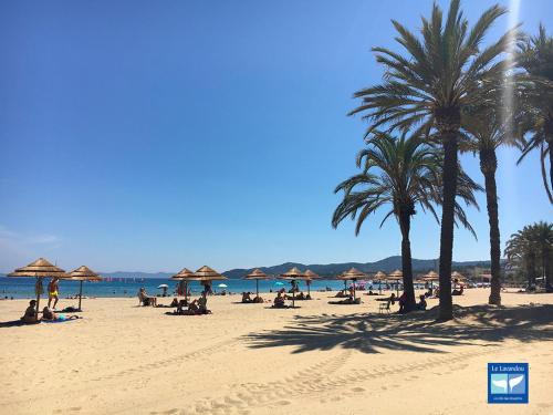 um grupo de pessoas sentadas numa praia com guarda-sóis em T2 rue piétonne Le Lavandou climatisé em Le Lavandou