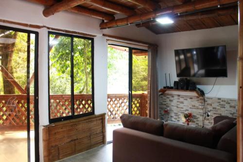 un salon avec un canapé et une télévision à écran plat dans l'établissement hermosa cabaña villa majo, cuenta con el espectacular rio santo domingo, à San Francisco
