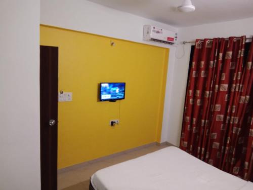 a room with a yellow wall with a tv on it at Hotel Nandanvan by Royal Stay in Lonavala