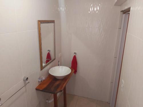 a white bathroom with a sink and a mirror at Recanto das Cerejeiras in Campos do Jordão