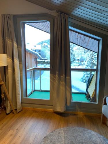 a room with two windows with a view of a balcony at LES COMBETTES in Les Contamines-Montjoie