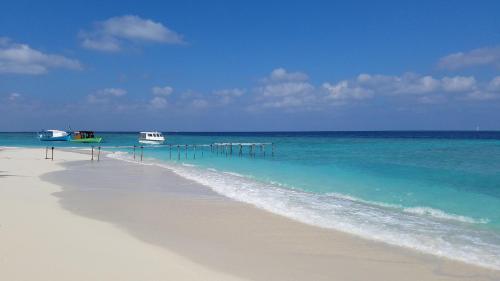 a beach with a pier in the water at PRIV Fodhdhoo in Fodhdhoo