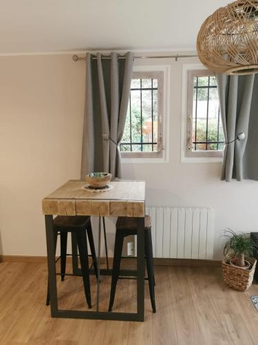 a dining room table with two stools in a room at Superbe studio cocooning au cœur de la Sologne. in Nouan-le-Fuzelier