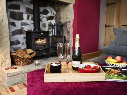 una botella de vino y copas en una mesa con chimenea en The Yorkshire Hosts - Come Home Cottage, en Haworth