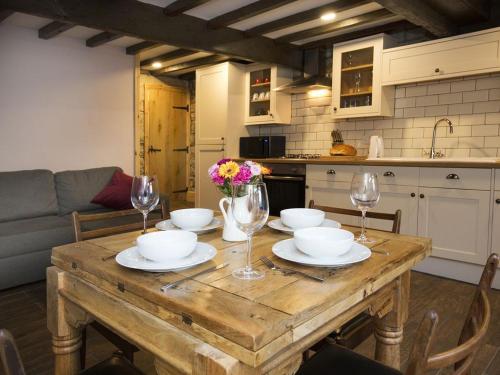 a wooden table with bowls and wine glasses on it at The Yorkshire Hosts - Come Home Cottage in Haworth