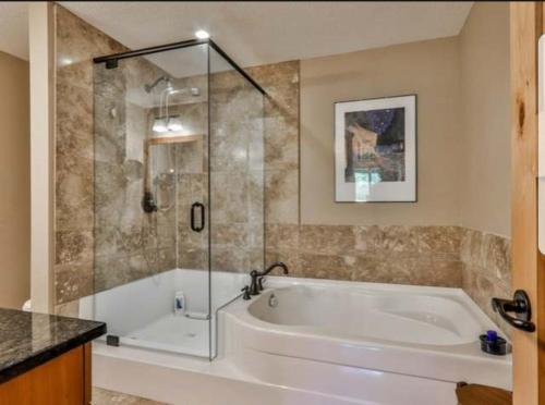 a bathroom with a tub and a glass shower at Luxurious Rundle Cliffs Lodge in Spring Creek in Canmore