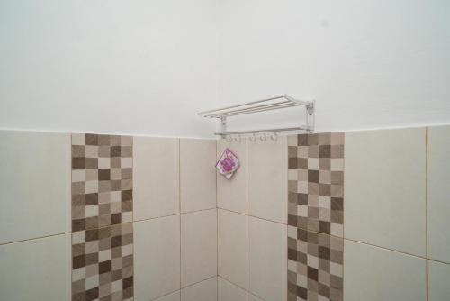 a shower with brown and white tiles in a bathroom at RedDoorz Syariah near Kota Cinema Mall Jatiasih 
