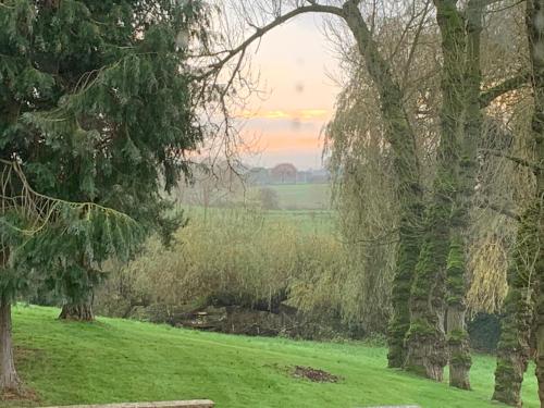 a grassy field with trees and a river at Fantastic Location, Annexe with Hot Tub in Warmingham