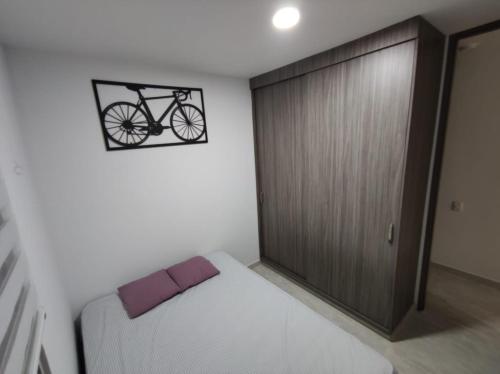 比亞維森西奧的住宿－Encantador y acogedor apto amoblado villavicencio，卧室配有一张床,墙上挂着自行车